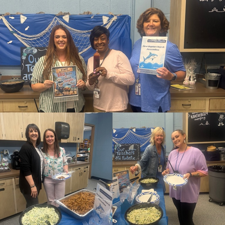 staff smiling in front of a catered lunch including rolls, macaroni and cheese, coleslaw and pulled pork  