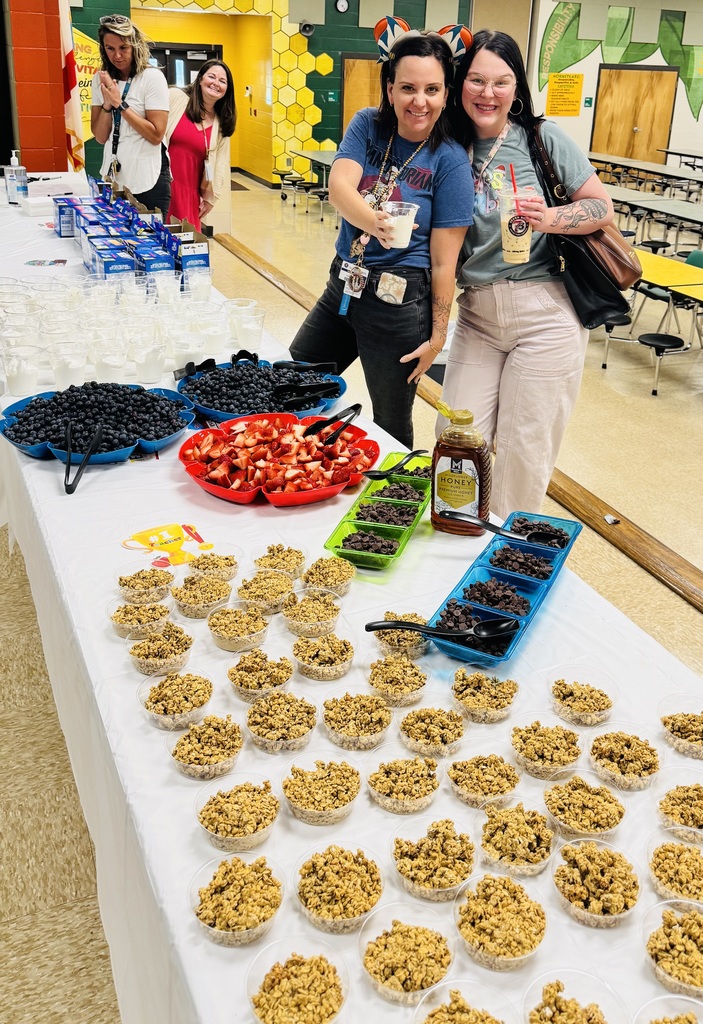 Teachers and staff smiling as they look on at the yogurt parfaits and blueberries and strawberries and poptarts for breakfast. 