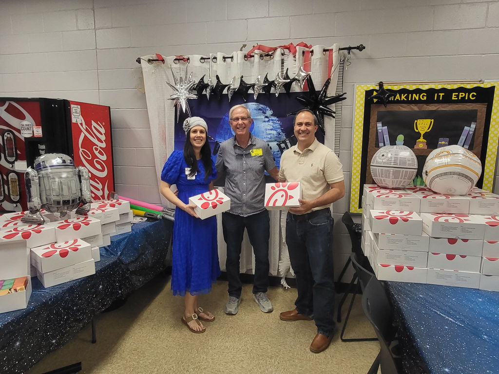 Dr. Weber posing with two men from First Baptist Church of Fernandina holding Chick-fil-A boxes. The three of them are standing in front of stacks of Chick-fil-A boxes surrounded by Star Wars decorations.