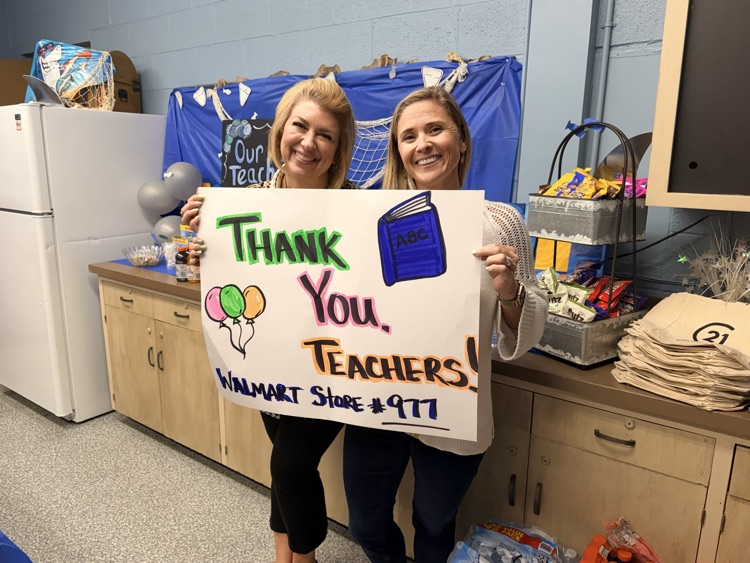 2 ladies smiling holding a sign saying Thank You Teachers  