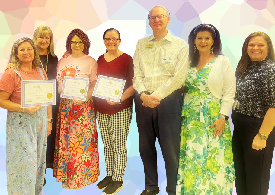 Seven adults standing smiling.  Three are holding certificates.  One is a male and the other six are females.