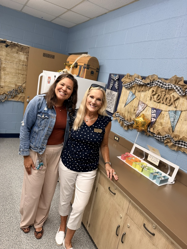 A blonde lady and a brown hair lady standing together, smiling