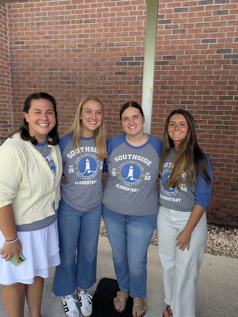 Four Southside Elementary educators stand outside together, smiling in matching school spirit shirts before beginning the day's professional learning activities.