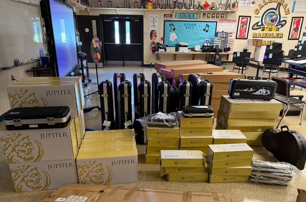 Newly delivered Jupiter-brand musical instruments and instrument cases are organized in a music classroom, showing a large shipment of equipment ready for student use.
