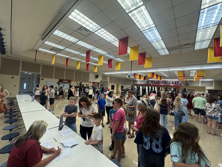 Parents and students gather in the school cafeteria during a meet-and-greet event. 