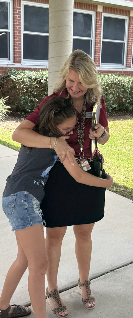 A student gives Ms. Boatright, the principal,  a hug outside the school building during a back-to-school event. 