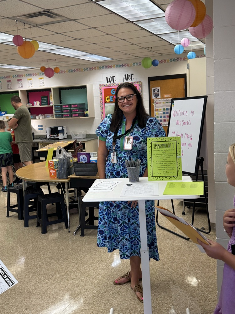 Mrs. Smith smiles as she welcomes students and their families into her decorated classroom during a back-to-school meet-and-greet.
