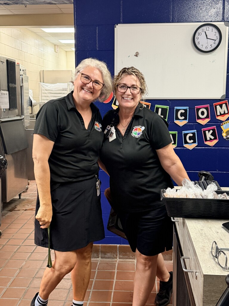 Two cafeteria workers smile for the camera on the first day back to school.