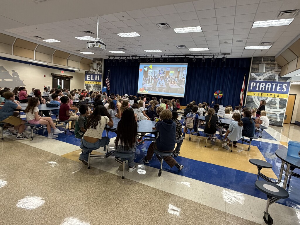 Students and teachers at a back to school pep rally in the cafeteria.