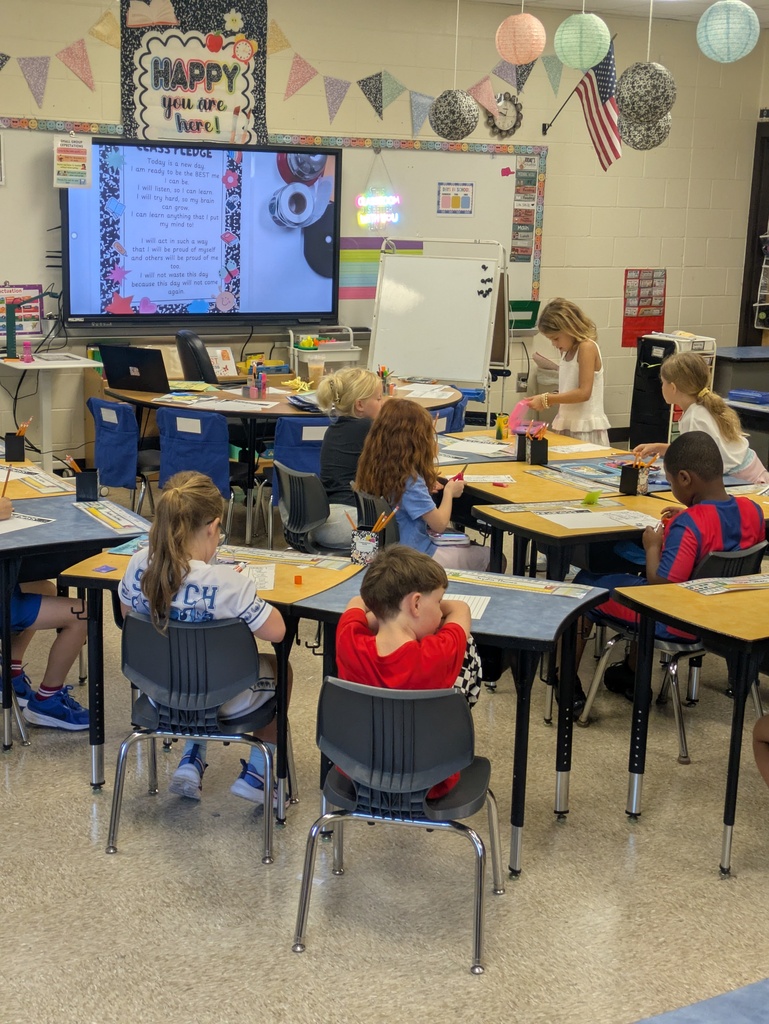 Students are sitting at their desk that curves around the smart panel in the classroom.