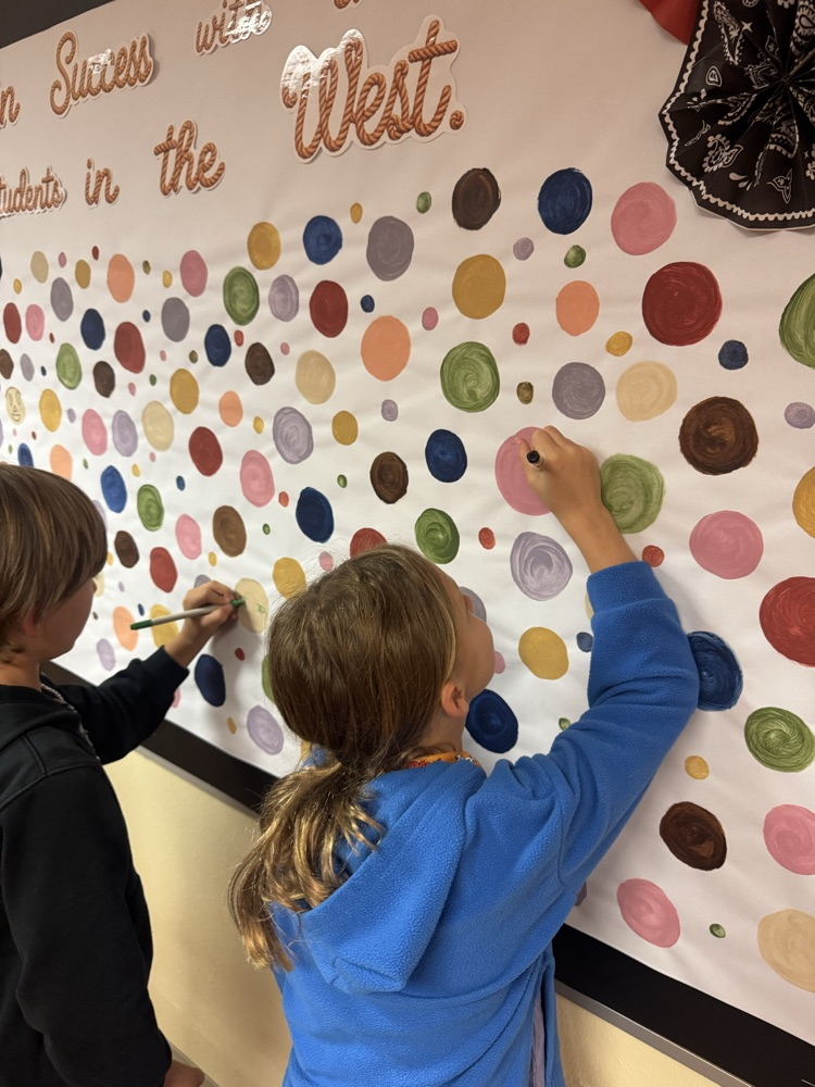 Students add their own creative drawings to a colorful collaborative bulletin board filled with painted circles. Working together, they transform the display into a celebration of student creativity, individuality, and school community.