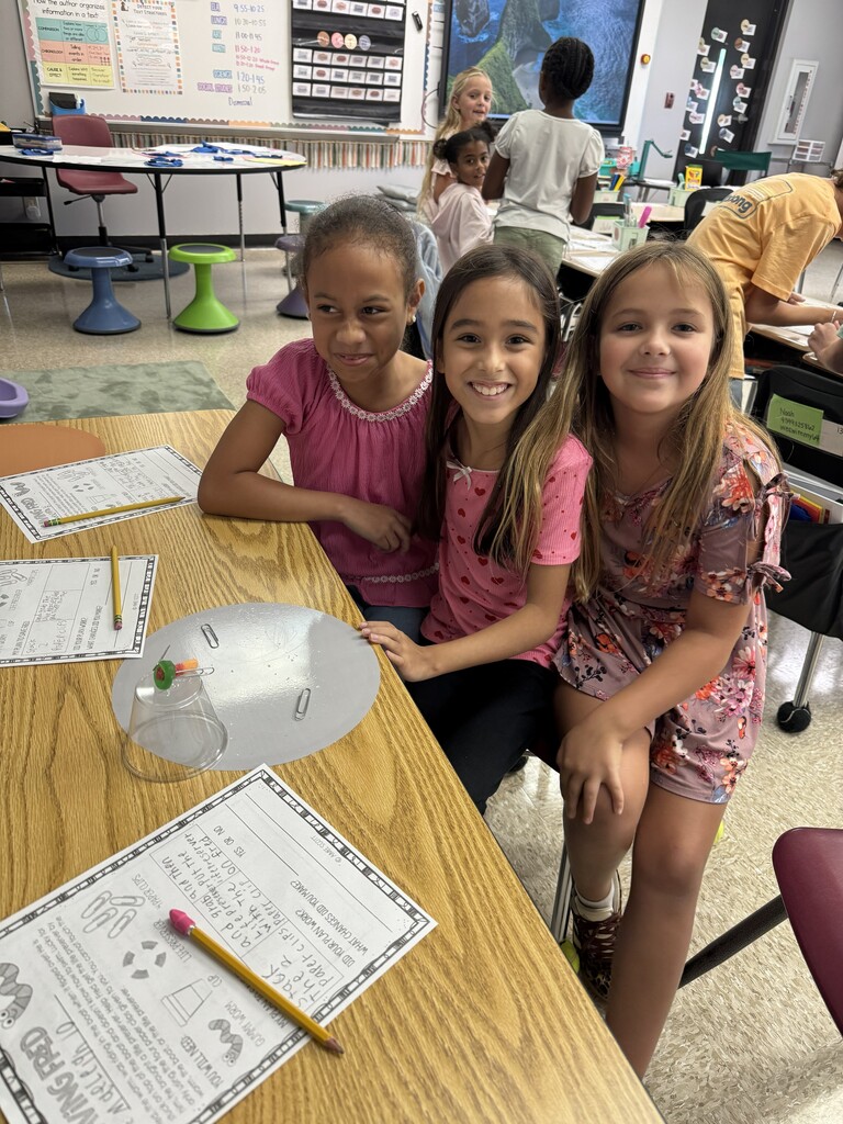 Students work to use a paperclip to pull a gummy worm through a life saver.