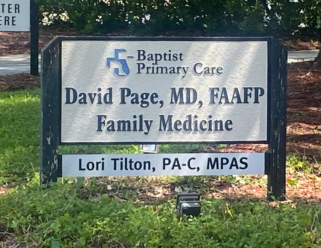 Sign outside Baptist Primary Care identifying the practice of Dr. David Page, MD, FAAFP, Family Medicine, with Lori Tilton, PA-C, MPAS, listed below. The practice serves patients in Nassau County and is owned by Fernandina Beach High School alumnus Dr. David Page.