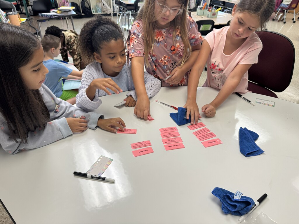 4 students at a table working on a text structure sort. 