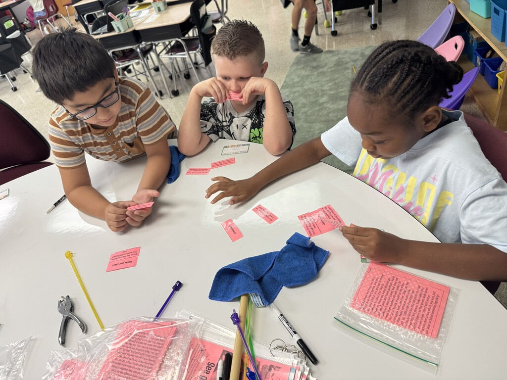 3 students working to complete a sorting activity at teacher table.