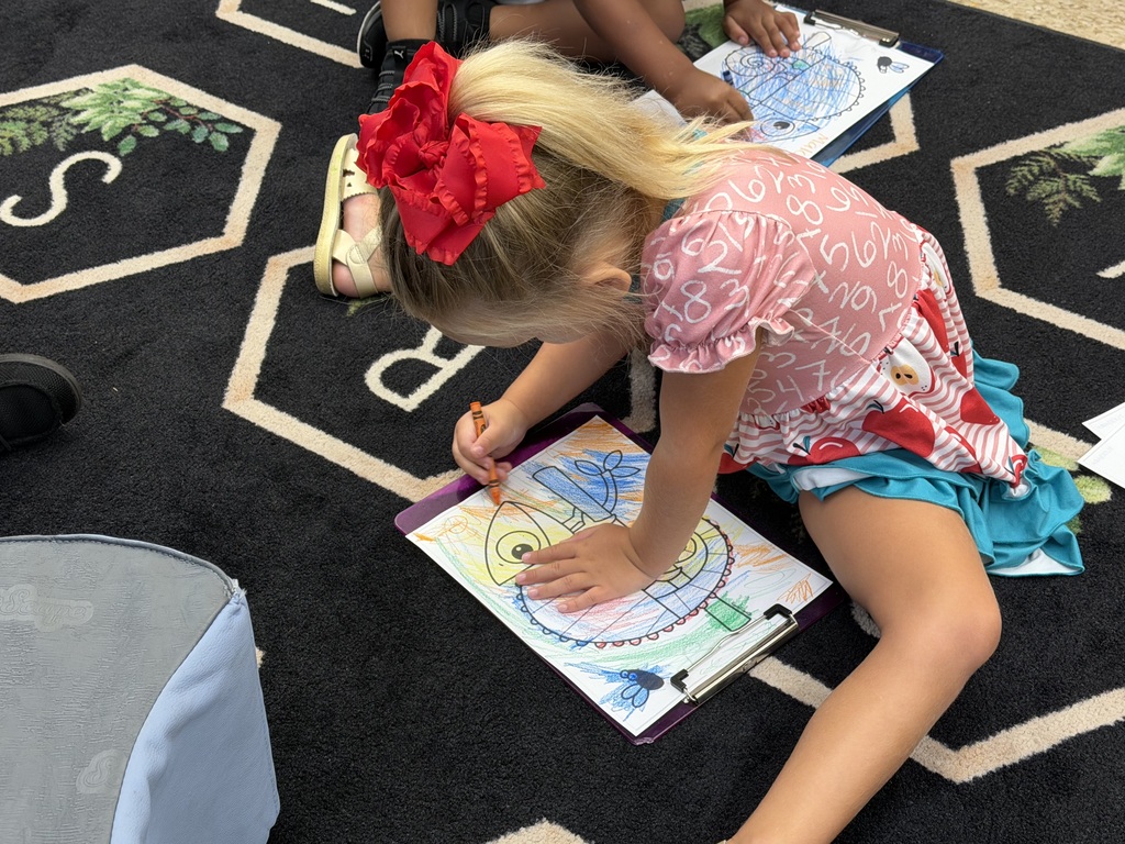 student sitting on a black rug coloring a picture