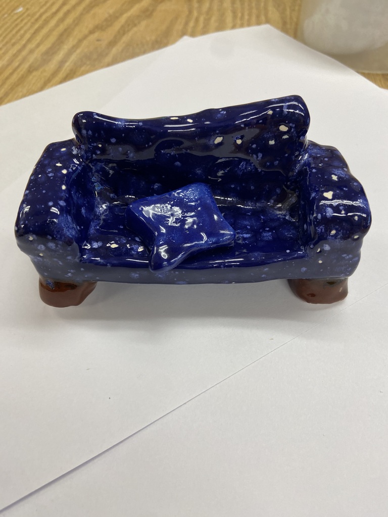 Student ceramic sample: Blue ceramic couch-shaped vessel on four legs with a star-shaped cushion and white speckled details.