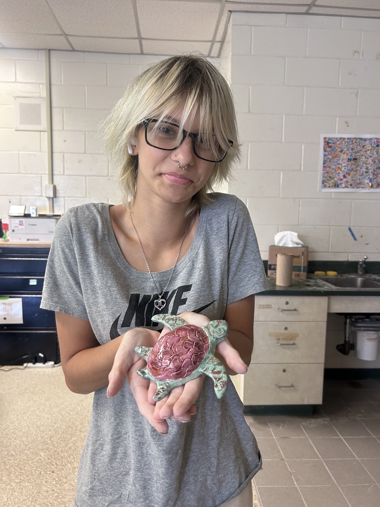 A ceramics student with their work