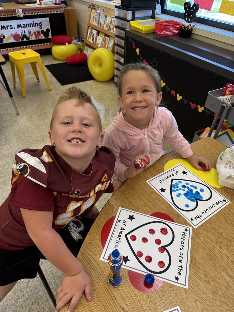 Elementary students smiling while working on a heart craft