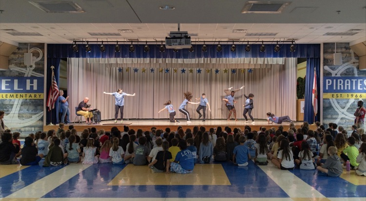 professional dancers performing improv dance on stage while a group of students watch