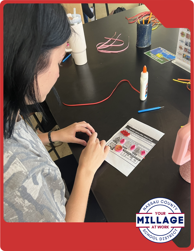 Students are learning to roll, shape, and arrange thin strips of paper into intricate designs, turning simple materials into beautiful works of art.