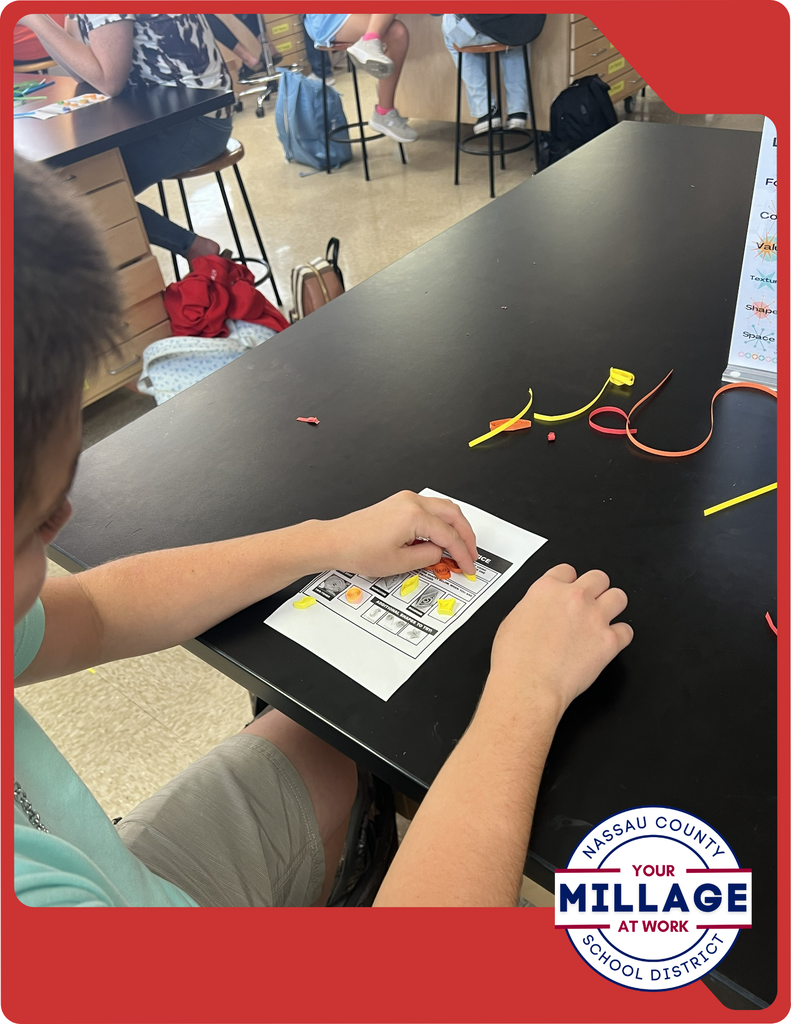 Students are learning to roll, shape, and arrange thin strips of paper into intricate designs, turning simple materials into beautiful works of art.