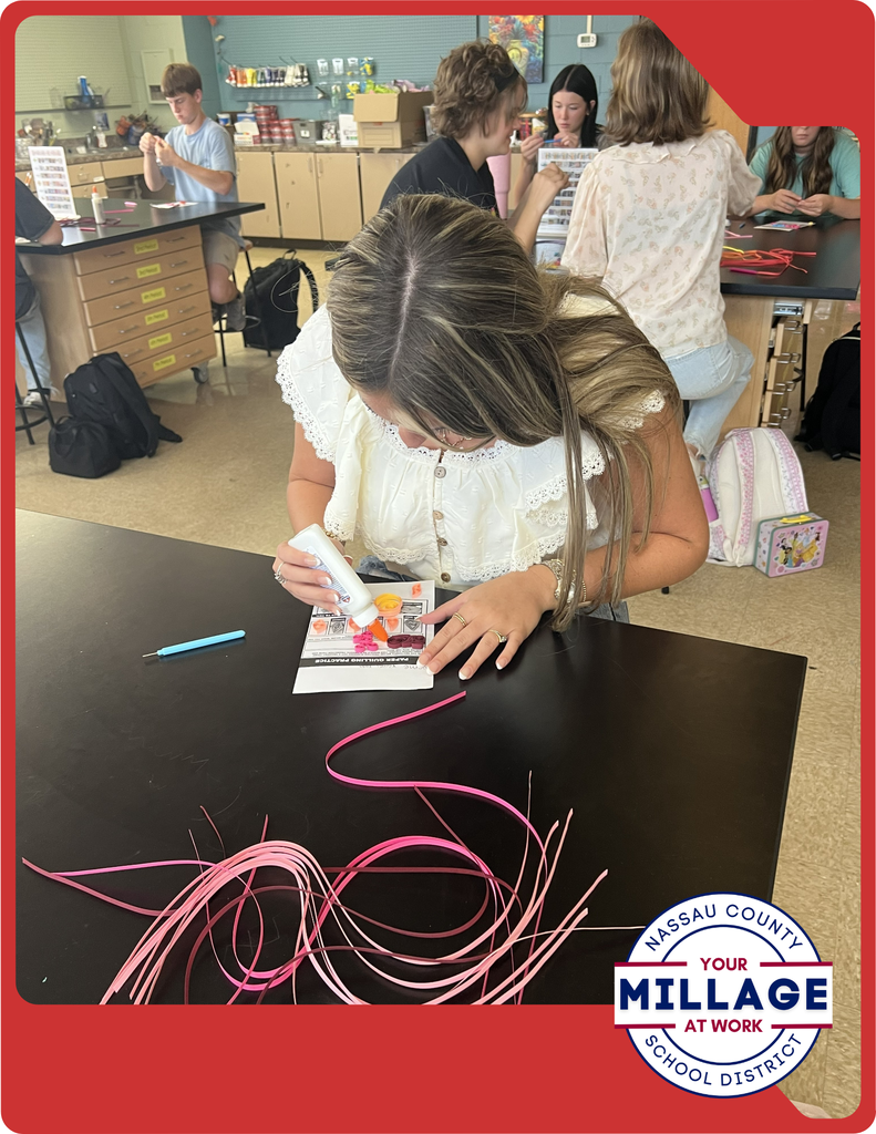 Students are learning to roll, shape, and arrange thin strips of paper into intricate designs, turning simple materials into beautiful works of art.