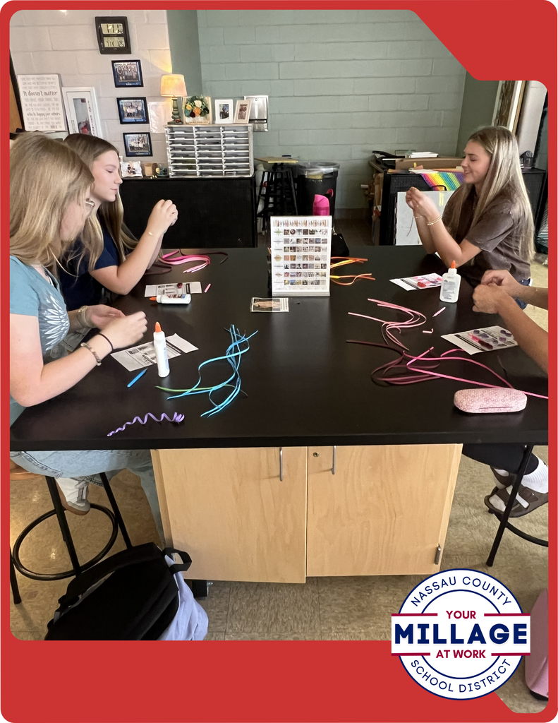 Students are learning to roll, shape, and arrange thin strips of paper into intricate designs, turning simple materials into beautiful works of art.