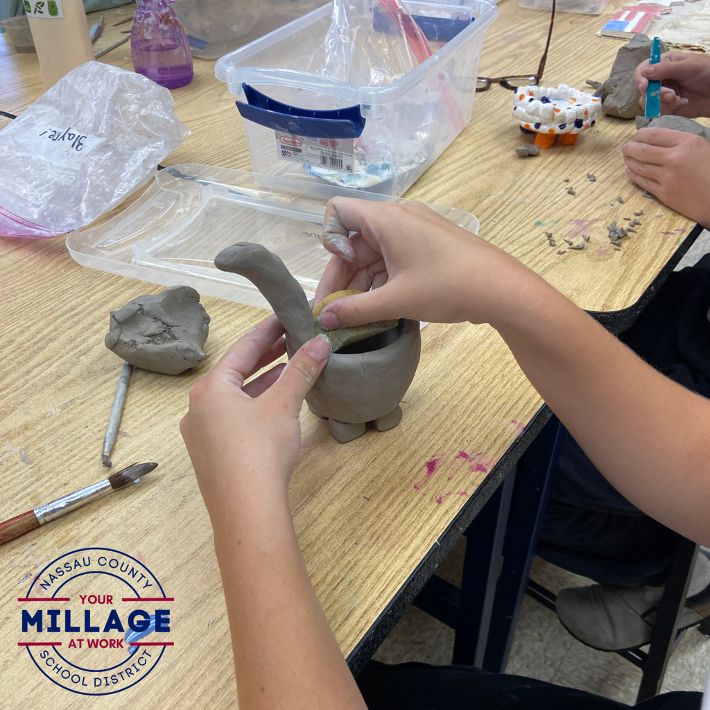 Student shapes a small clay vessel during a hands-on pottery activity in an art classroom.
