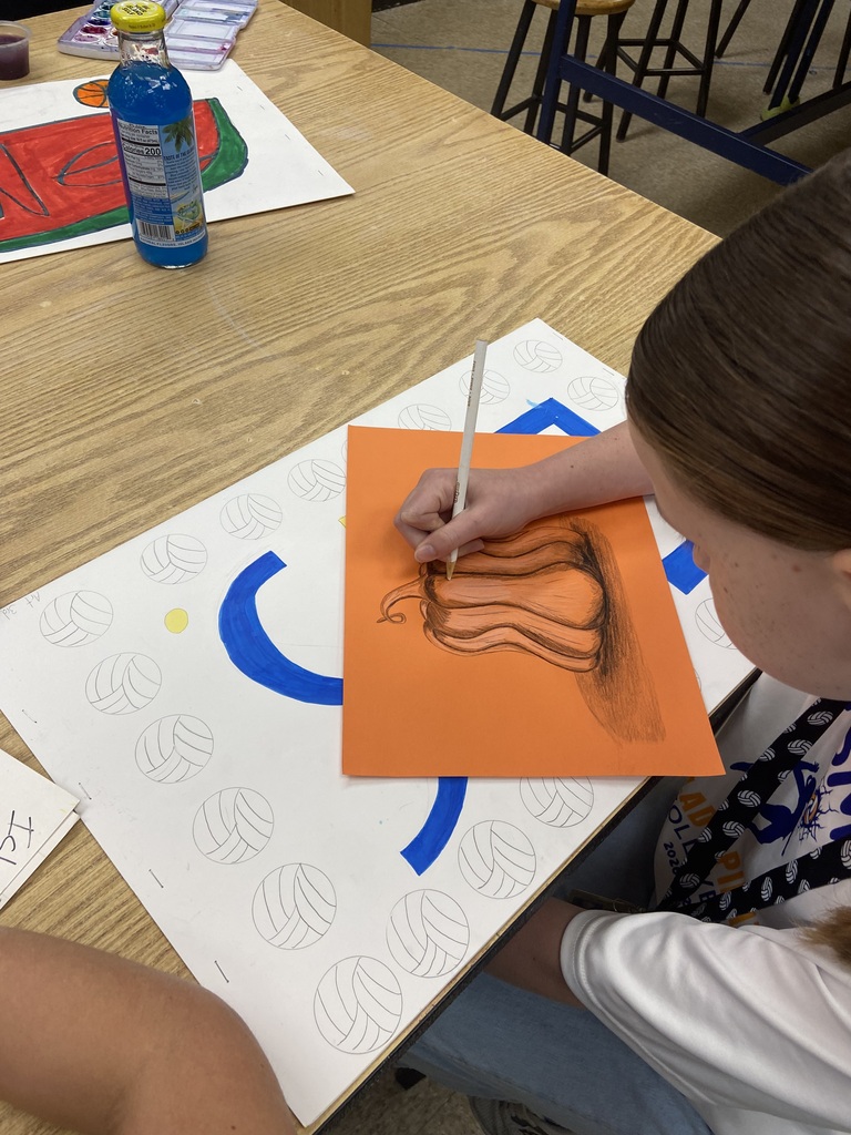 Student making a pumpkin drawing on orange paper.