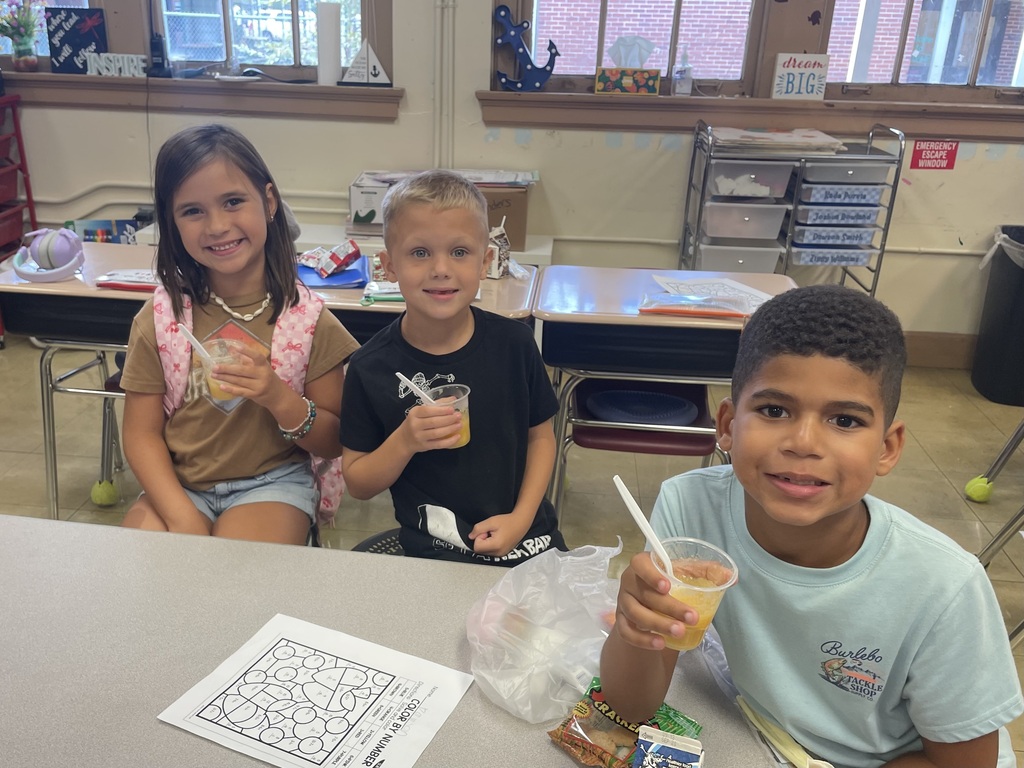 three students holding up a cup of applesauce