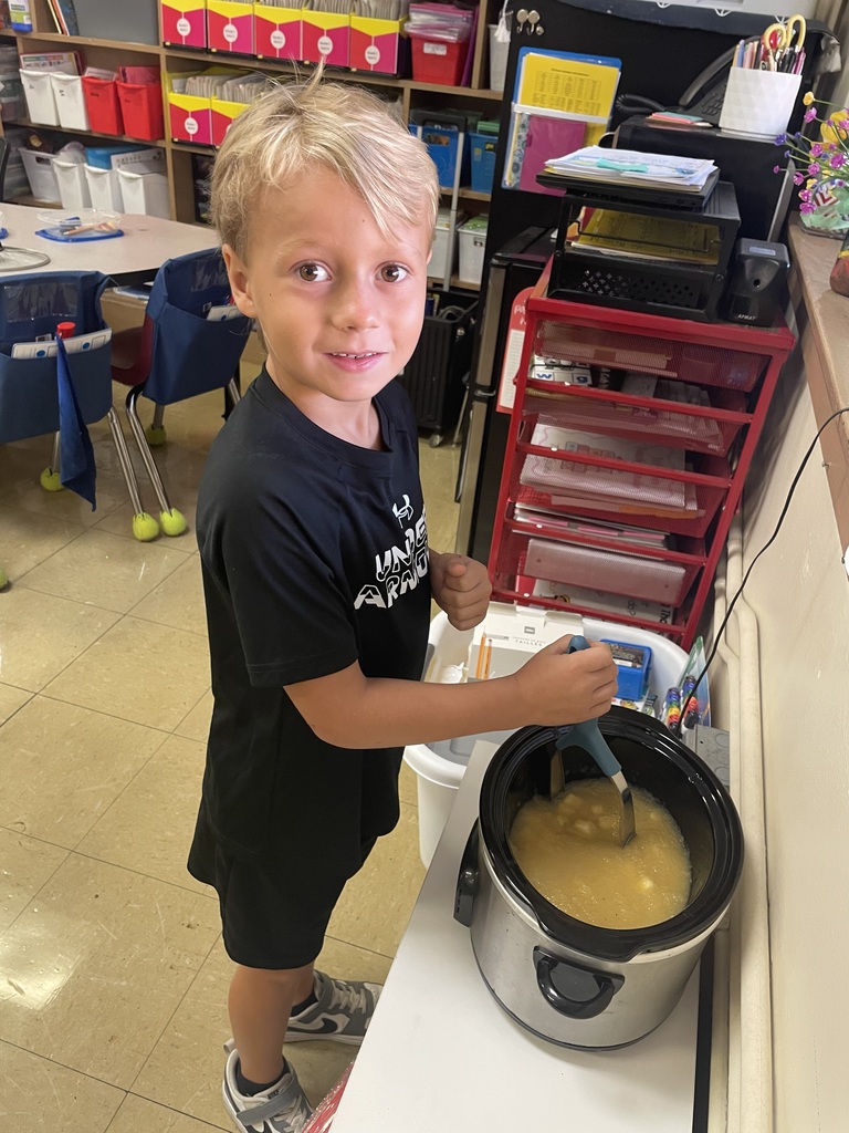 boy stirring a pot of apples