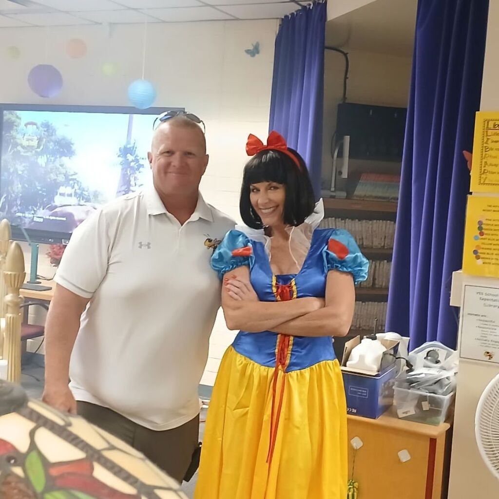 Coac Tate and M.s Soli (dressed as snow white) set up a library activity.