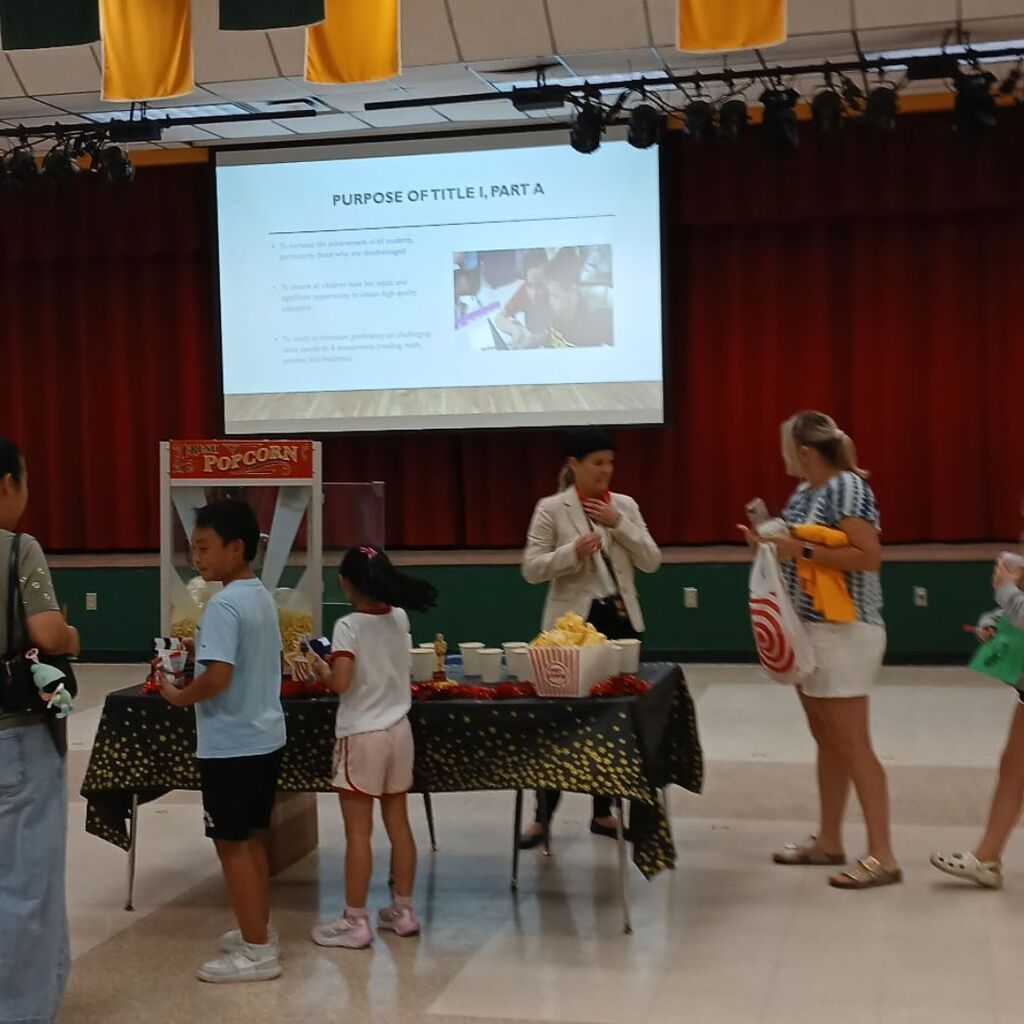 families participating in "Popcorn with the Principal" in the cafeteria while learning about school programs and opportunities.
