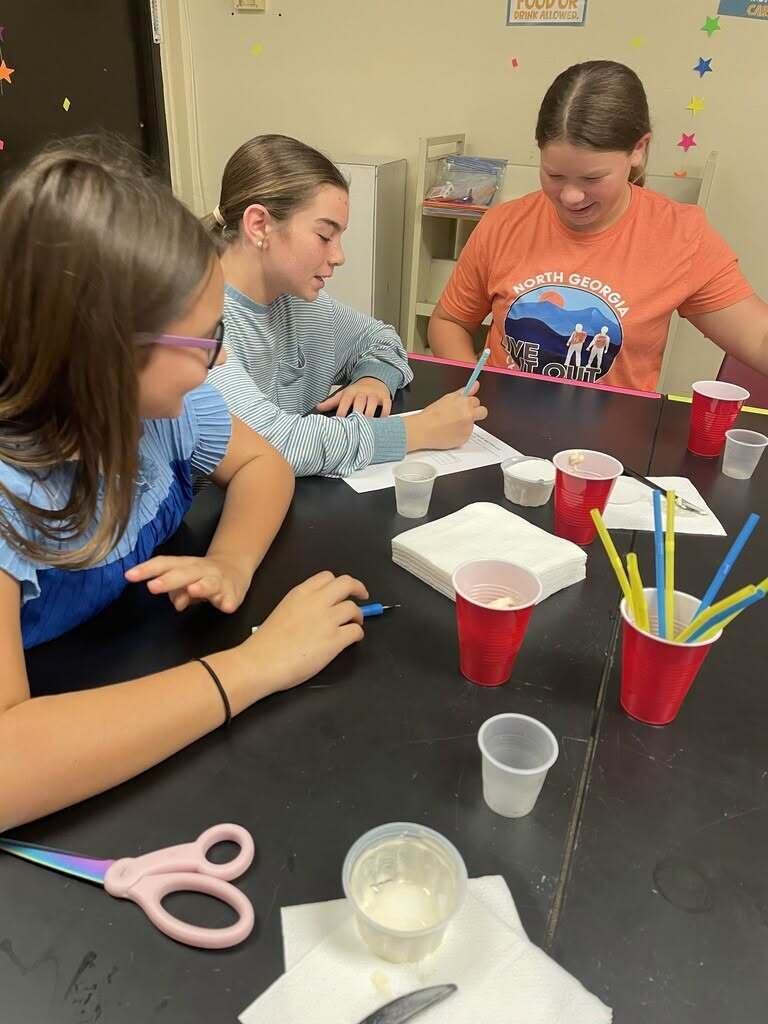 Three eighth-grade students at Hilliard Middle-Senior High School work together at a classroom table during a hands-on states of matter science lab.