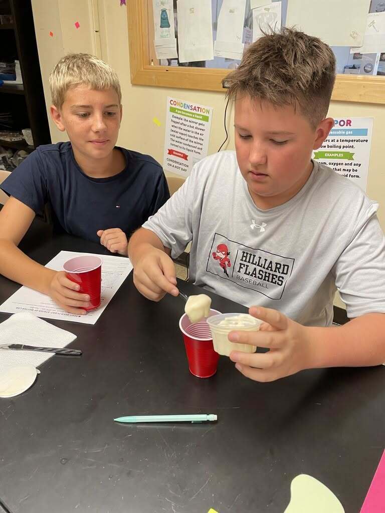 Two eighth-grade students at Hilliard Middle-Senior High School conduct a hands-on science activity using cups and materials during a states of matter lesson.