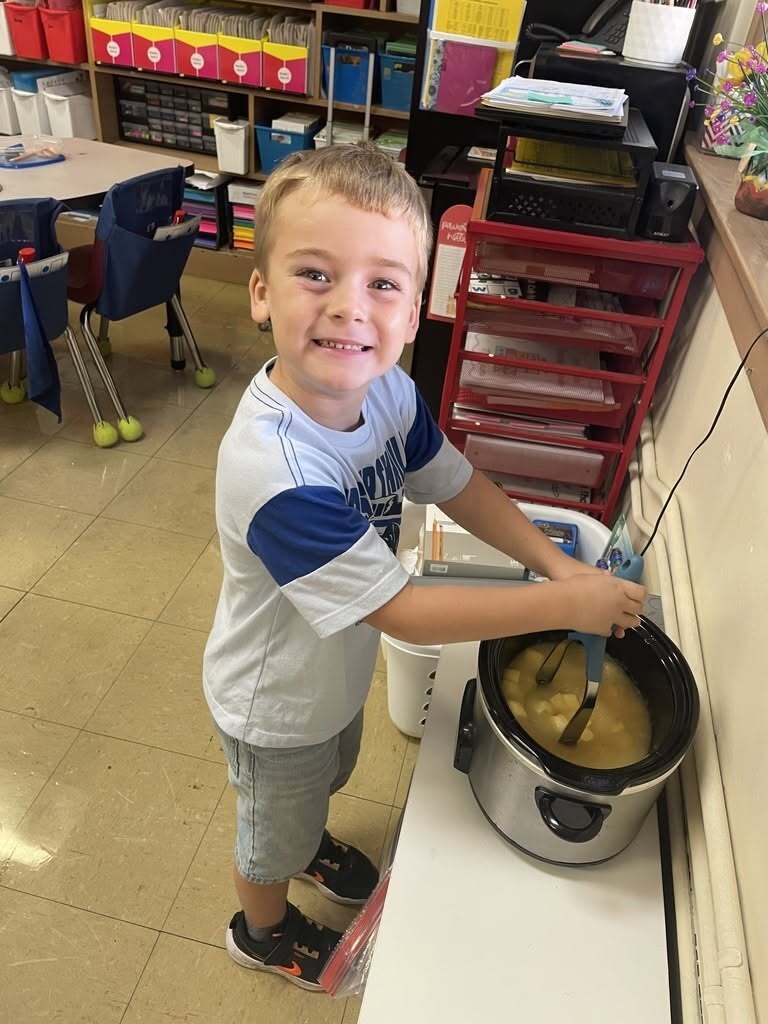 A first-grade student at Callahan Elementary School stirs apples in a slow cooker while the class makes homemade applesauce during Apple Day.