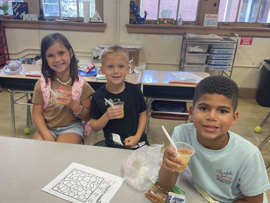 Three first-grade students at Callahan Elementary School enjoy homemade applesauce after participating in hands-on Apple Day learning activities.