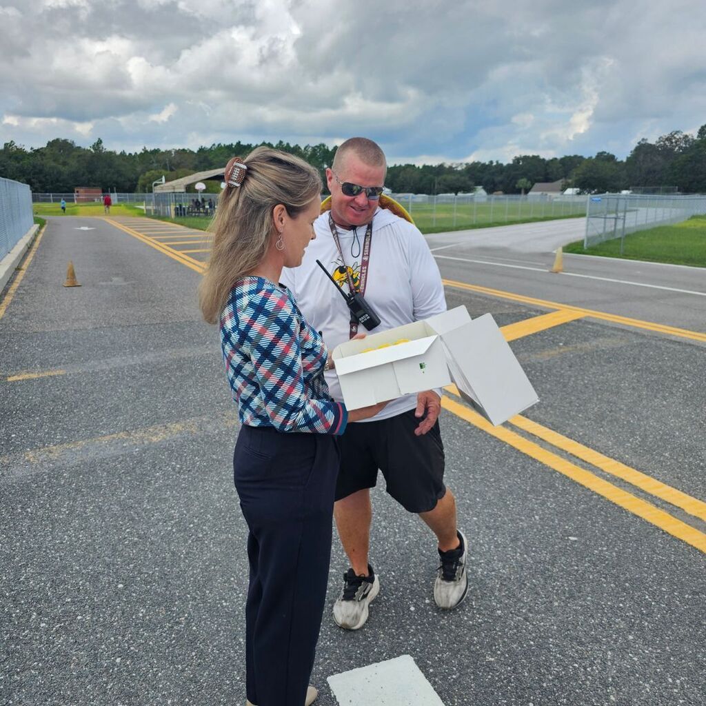Coach Tate and Mrs. Hays as he is presented with a cake that says Congratulations for being the 2026-2027 Teacher of the Year.