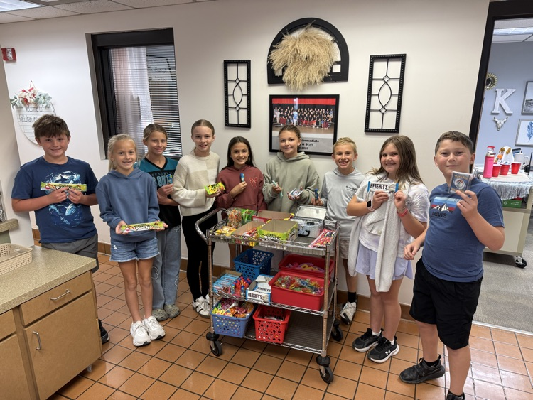 A group of students proudly hold up the prizes they selected from the Warrior Cart after demonstrating Respectful, Responsible, and Safe behavior.