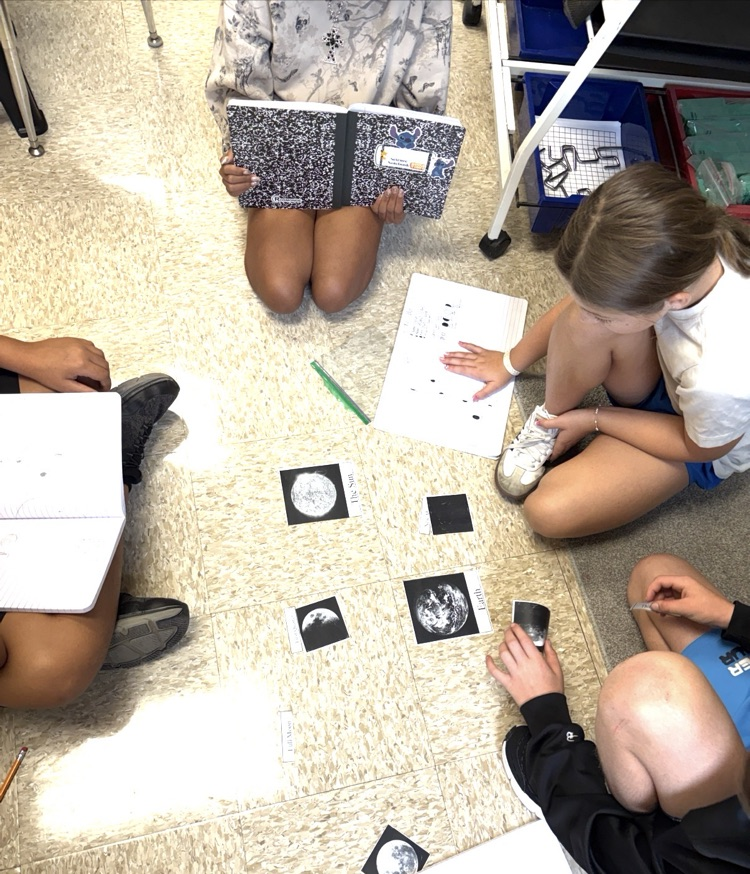 students working together sorting phases of the moon and recording notes in their journal