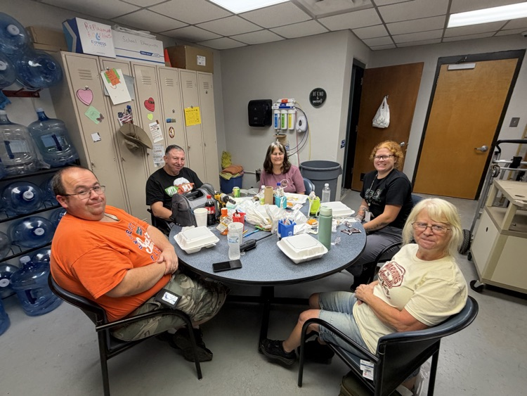 men qnd women sitting in a break room enjoying lunch and smiling 