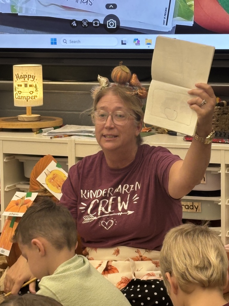 teacher holding up a writing journal as a model for the students