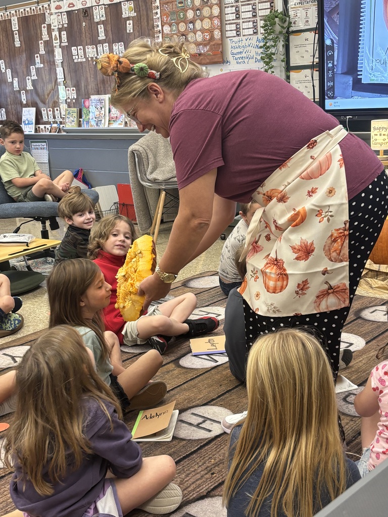 teacher holding the cut off top of a pumpkin and letting students smell it