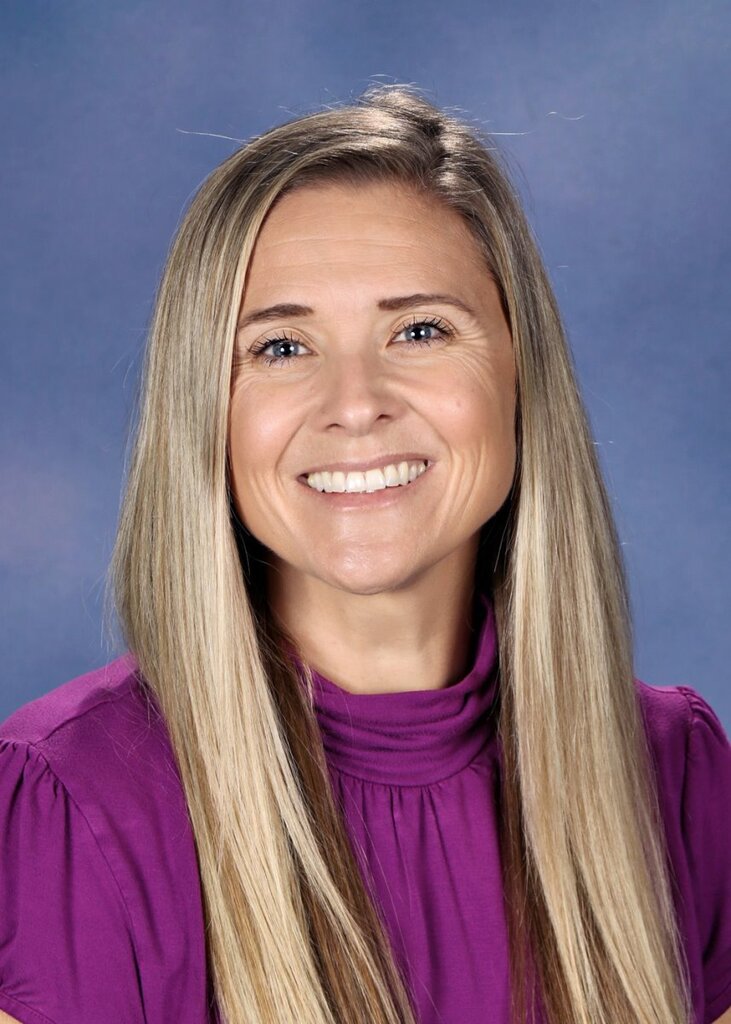 Picture of Karina Mikelson who has long blonde hair, smiling and wearing a purple shirt. 
