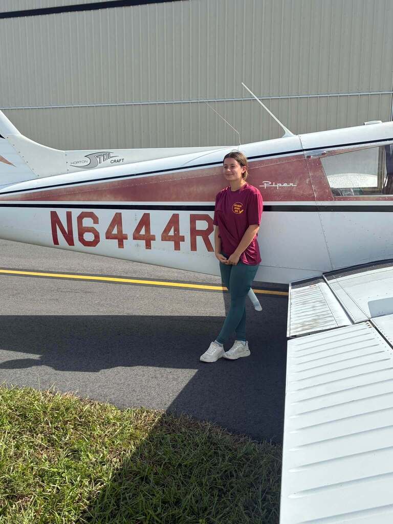 West Nassau High School student Scarlett Lynn stands beside a small single-engine airplane after completing her first solo flight through the district’s aviation program.