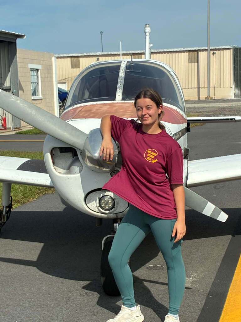 West Nassau High School student Scarlett Lynn stands beside a small single-engine airplane after completing her first solo flight through the district’s aviation program.