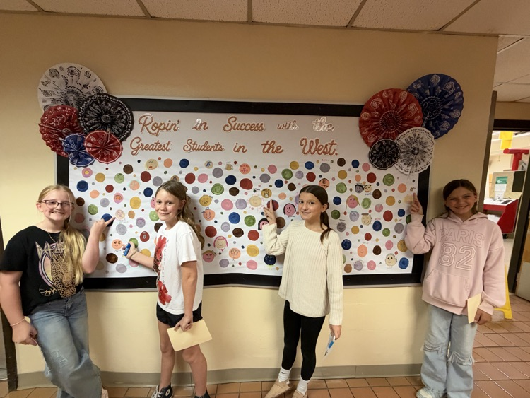 Students who received Warrior praise pointing towards their self-portrait dots.