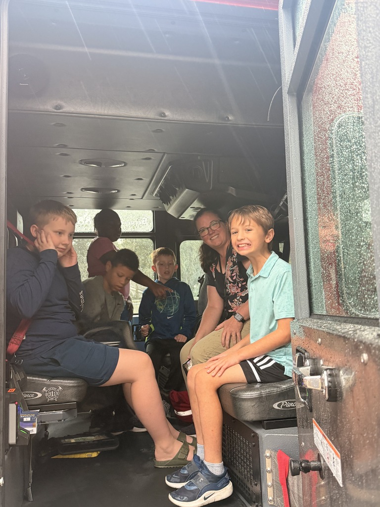 Students with their teacher sitting in the back of the fire truck.