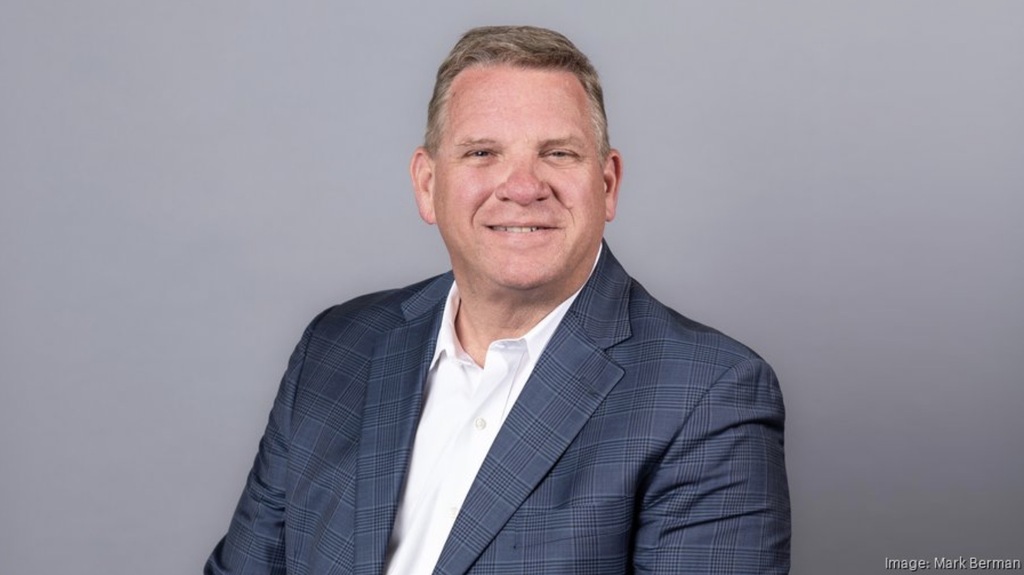 Professional portrait of Craig Smith, West Nassau High School’s 2026 Hall of Fame inductee. He is smiling and wearing a blue plaid blazer over a white collared shirt, posed against a plain gray background. Photo credit: Mark Berman.